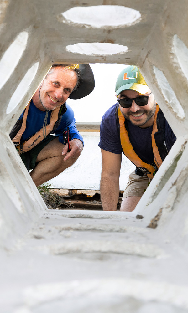 Haus and Rhode-Barbarigos peer through a six-foot-tall perforated SEAHIVE unit, which they designed with other faculty members, on the barge that lowered dozens of the units into the ocean.
